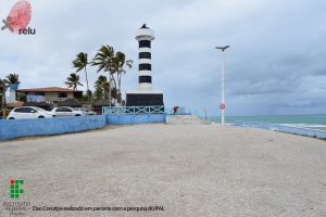 Foto do Farol visto de perto, mostrando a praia no lado direito