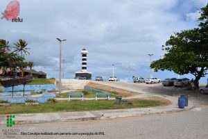 Foto do Farol visto de longe, mostrando uma praça