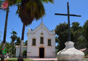 Foto da Igreja São José do Poxim vista de frente, de longe, mostrando uma cruz na frente dela